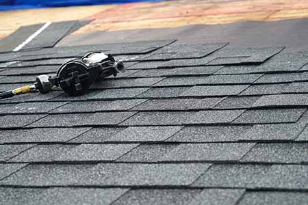 nail gun and asphalt shingles being installed